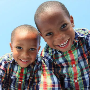 Two small children smiling at the camera in matching shirts.