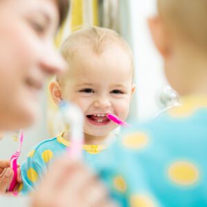 Toddler learning to brush teeth thanks to early pediatric dental care in Atlanta.