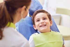 A little boy smiling at a dentist during treatment.
