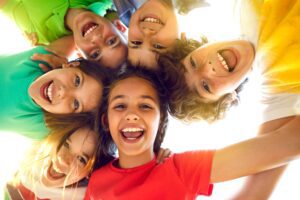 A group of children smiling while playing outside together.
